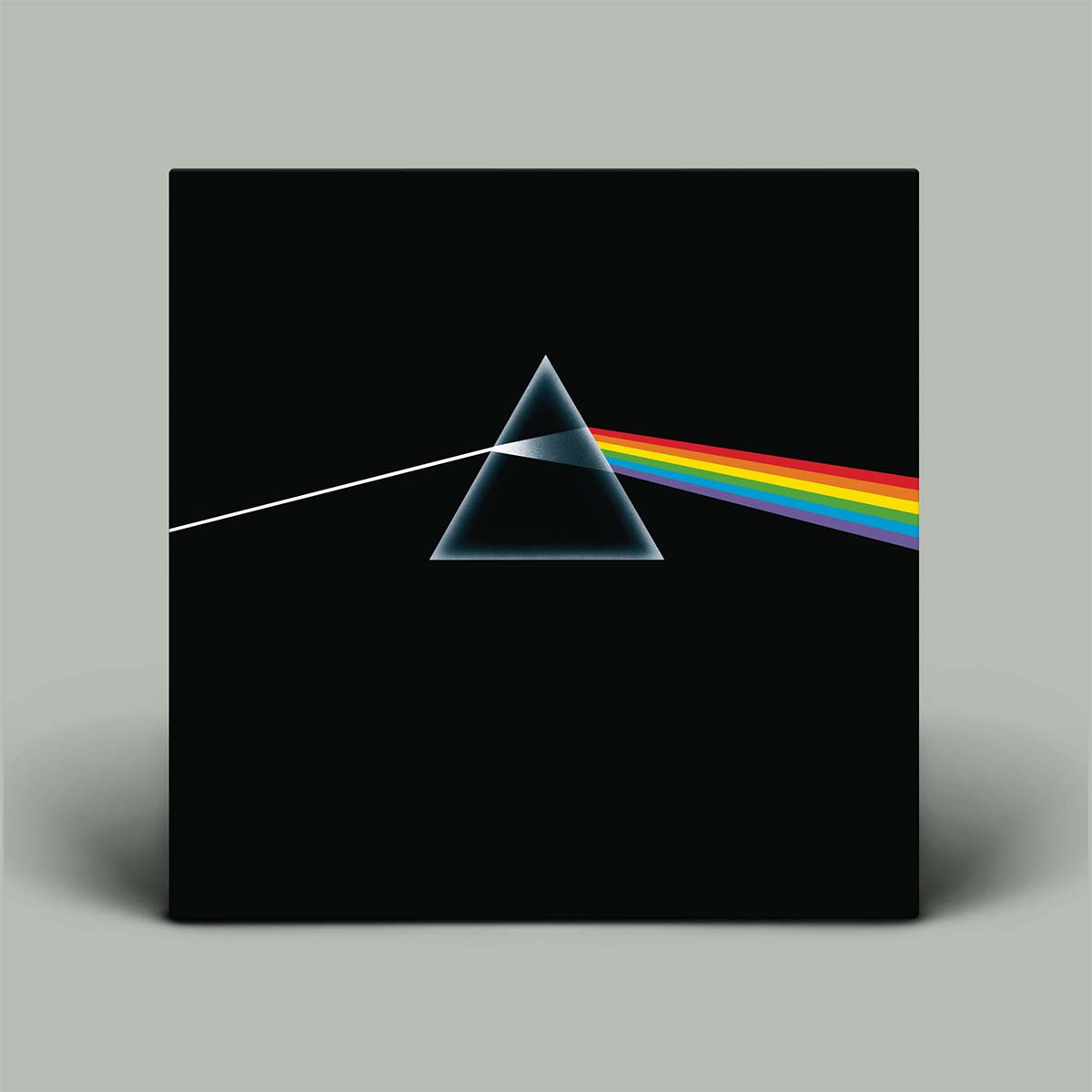 A square black canvas print featuring the classic Pink Floyd 'The Dark Side of the Moon' album cover art, including the white light beam and rainbow prism on a black background, shown against a neutral gray wall.