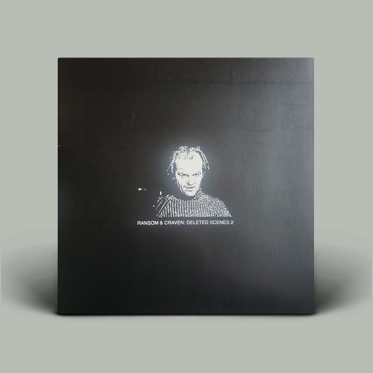 A square black box or package standing upright on a light gray background, with a white stylized portrait and the text 'RANSOM & CRAVEN DELETED SCENES 2' printed near the bottom center.
