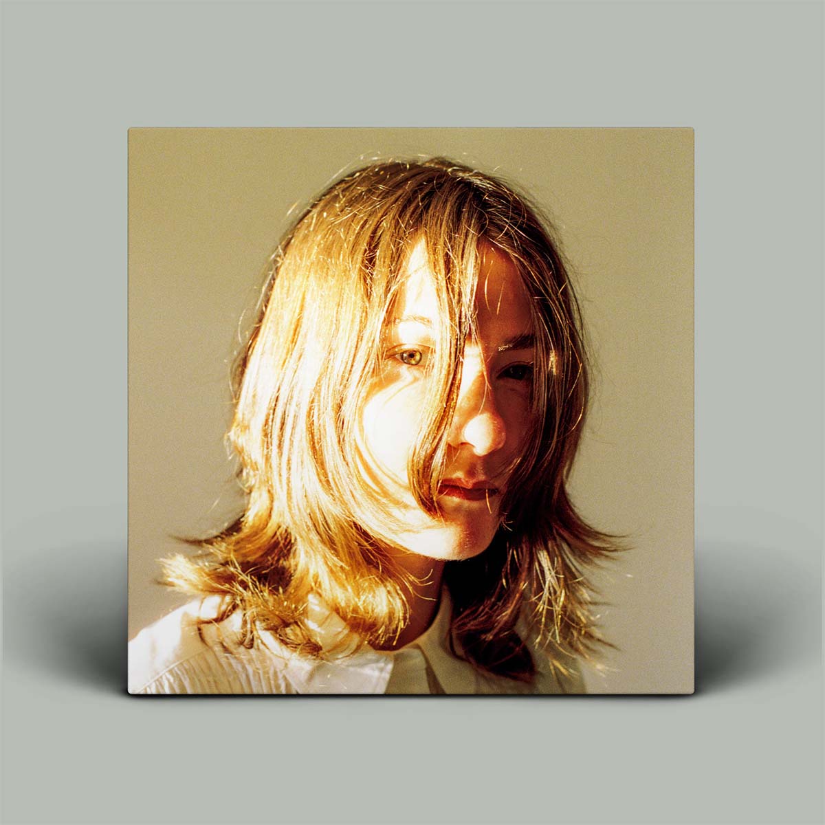 A square wall art print or canvas featuring a warm-toned portrait of a woman with shoulder-length light brown hair, shown against a plain light gray background.