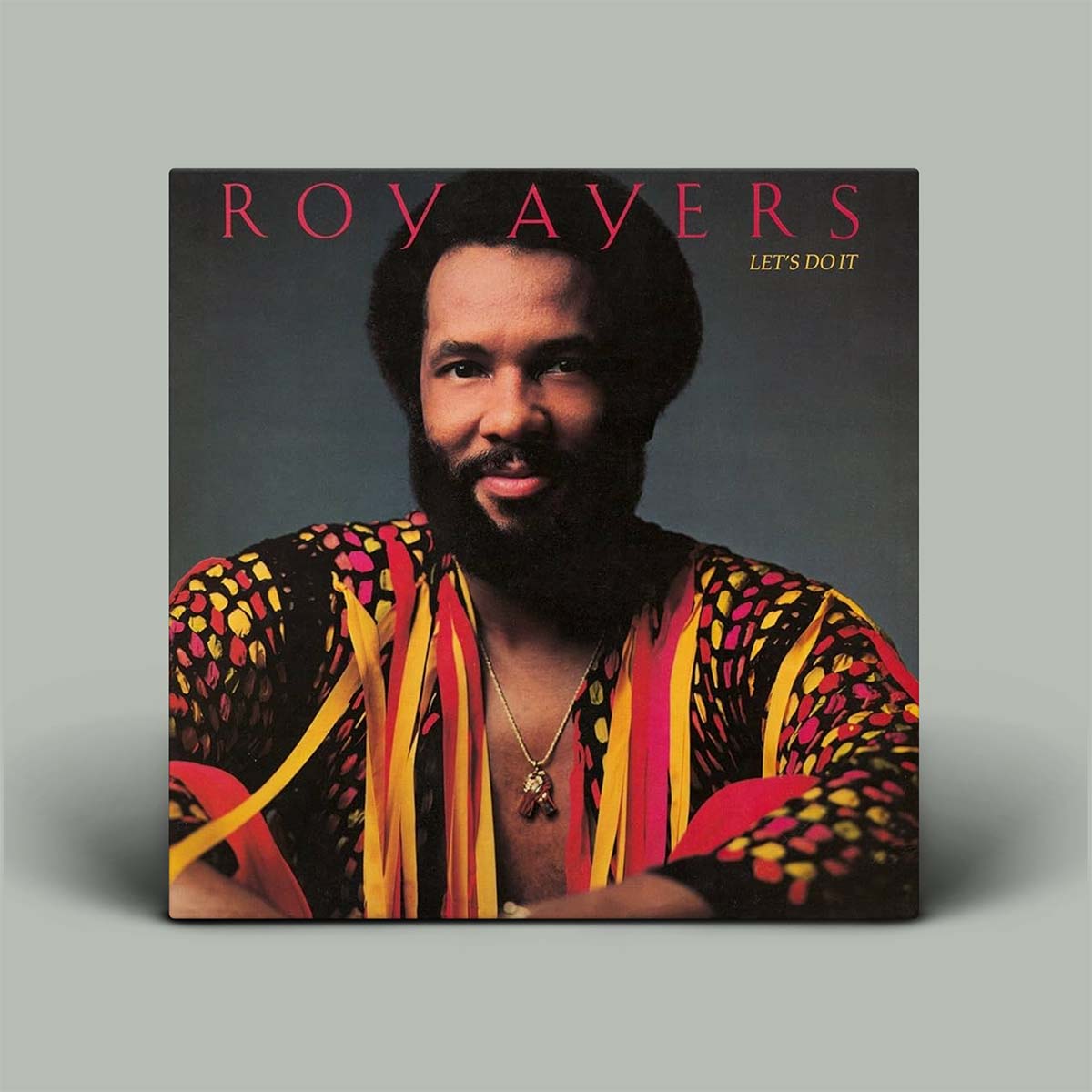 Album cover featuring a person with a colorful patterned shirt on a gray background