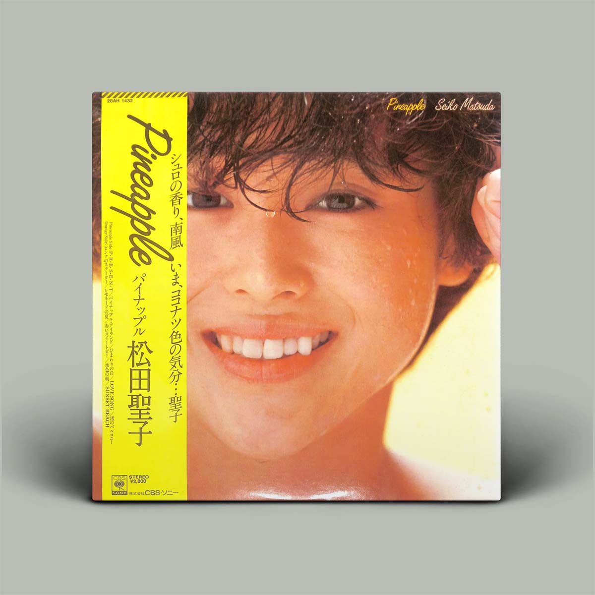 A vinyl record album cover for 'Pineapple' by Satsuki Taketora, featuring a bright yellow spine and a close-up portrait of the smiling artist on the front, shown against a neutral gray background.