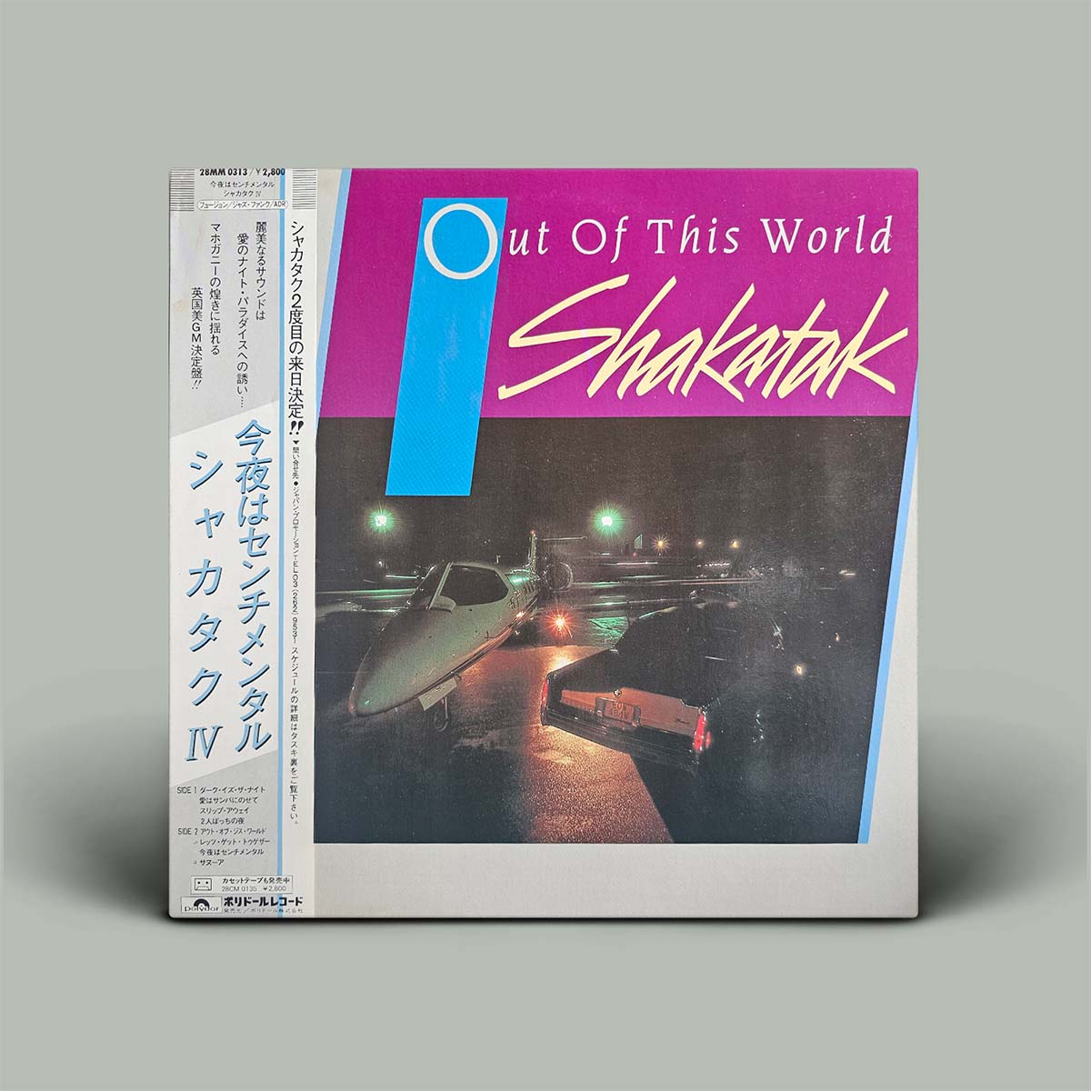 Shakatak's 'Out Of This World' Japanese vinyl LP album cover, featuring a magenta and blue design with a night photograph of a fighter jet on a runway, shown on a neutral gray background.