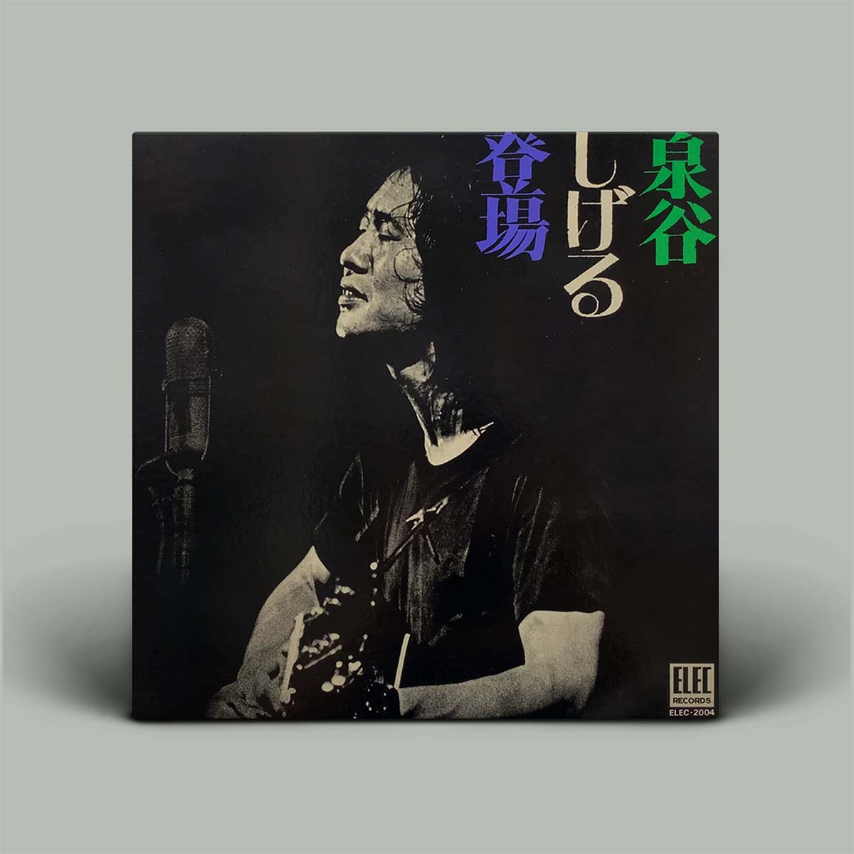 Vinyl record cover with a person and microphone, featuring Japanese text on a gray background