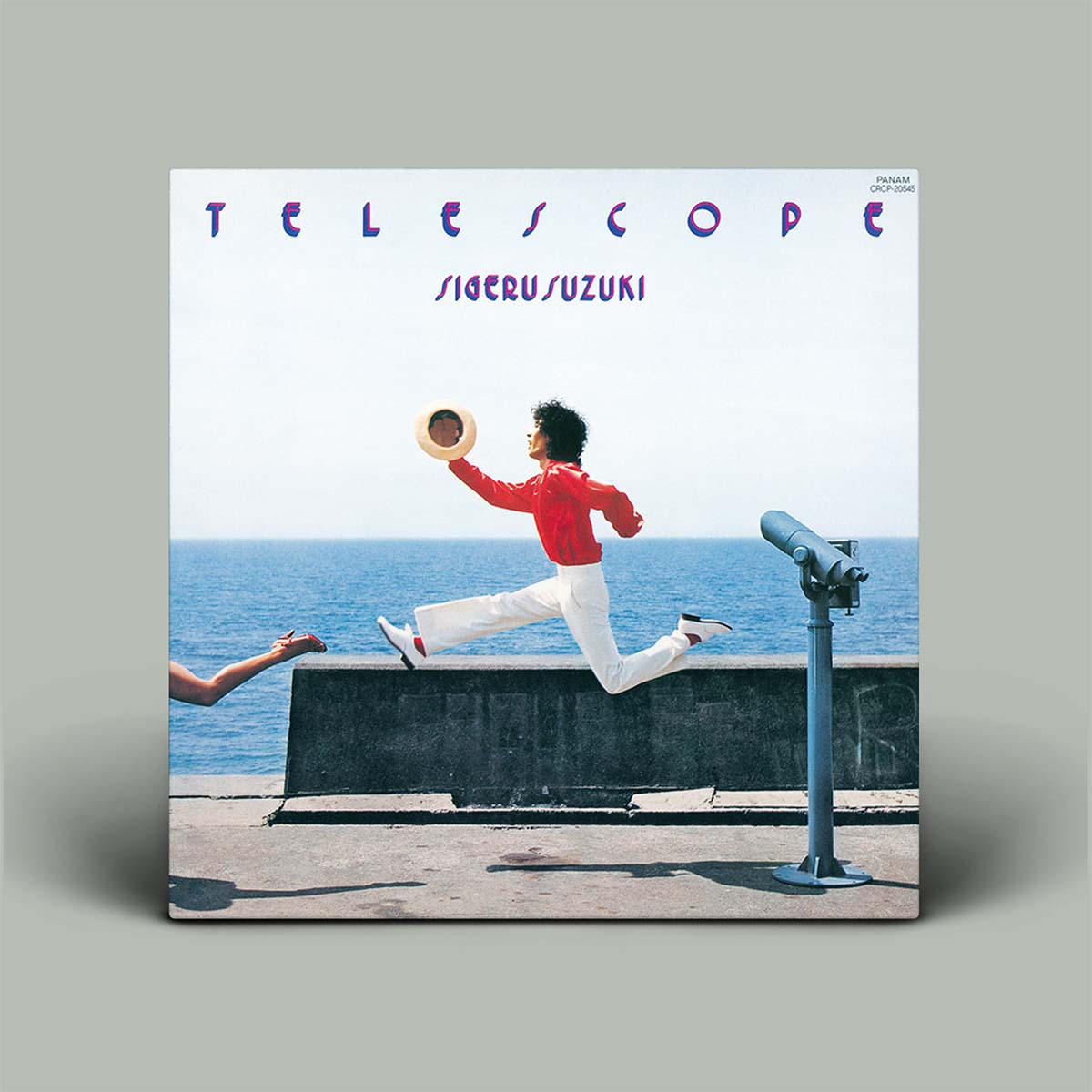 The album cover for 'Telescope' by Shigeru Suzuki, displayed as a physical vinyl record mockup against a solid gray background. The cover art features a man in a red shirt and white pants leaping over a concrete barrier with the ocean behind him, alongside a coin-operated telescope.