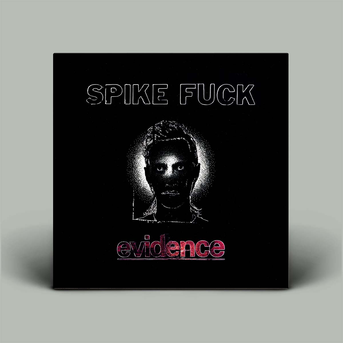 A square black album cover art piece with the text 'SPIKE FUCK' at the top and 'evidence' in pink at the bottom, featuring a stylized grayscale face illustration in the center, shown against a light gray background.
