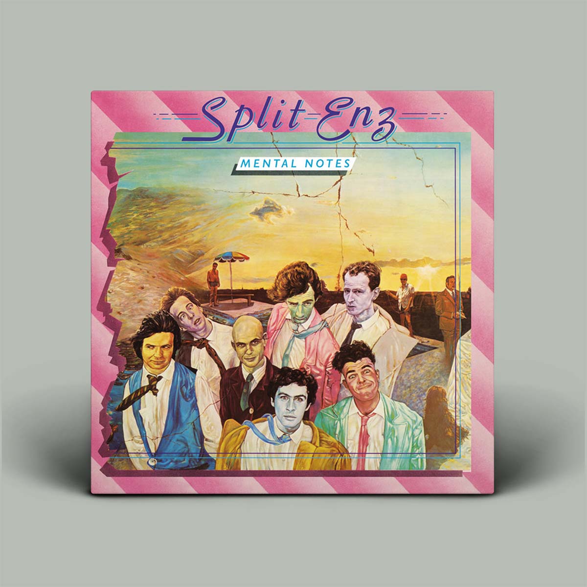 A vinyl record sleeve for the album 'Split Enz - Mental Notes' is shown standing upright on a neutral gray background. The cover features a colorful retro-style illustration of seven men in suits against a sunset beach scene, framed by a pink striped border.