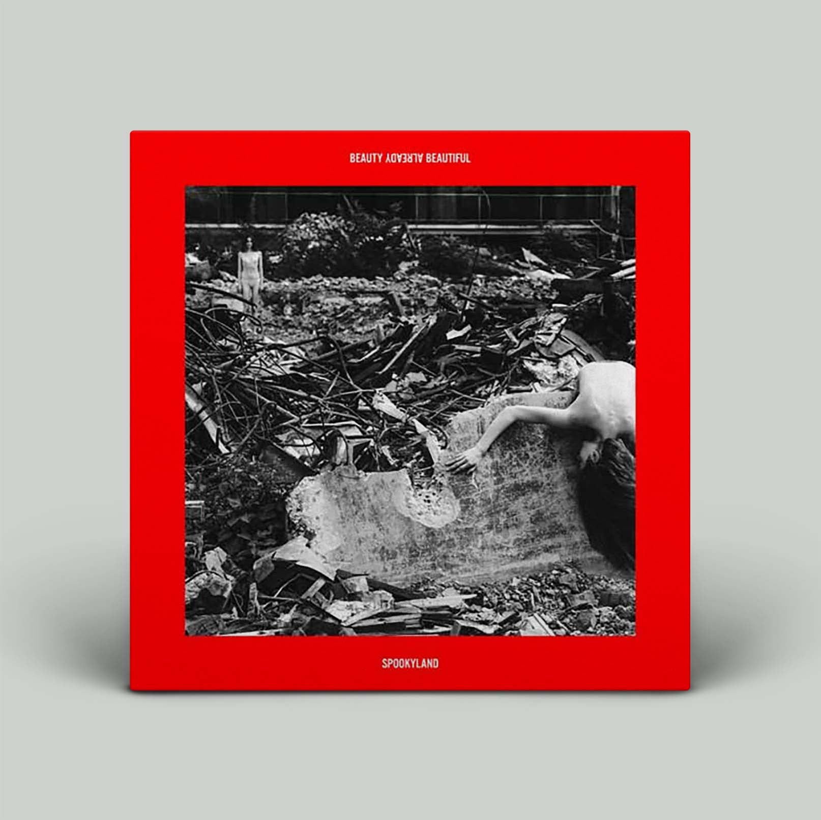 Album cover with black and white photo of person lying on rubble with red border.