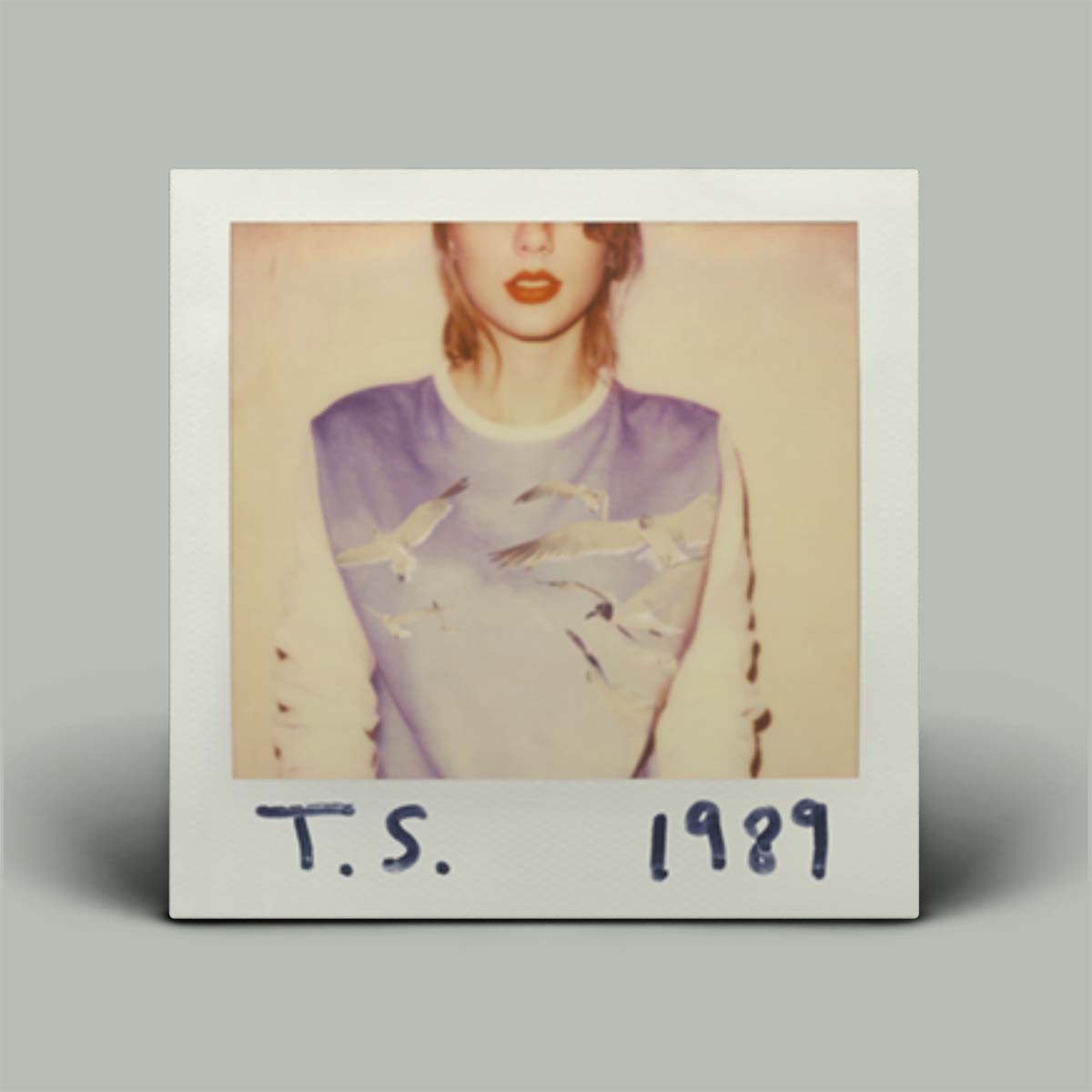 Album cover with a person wearing a purple and white outfit, labeled 'T.S. 1989' on a gray background.