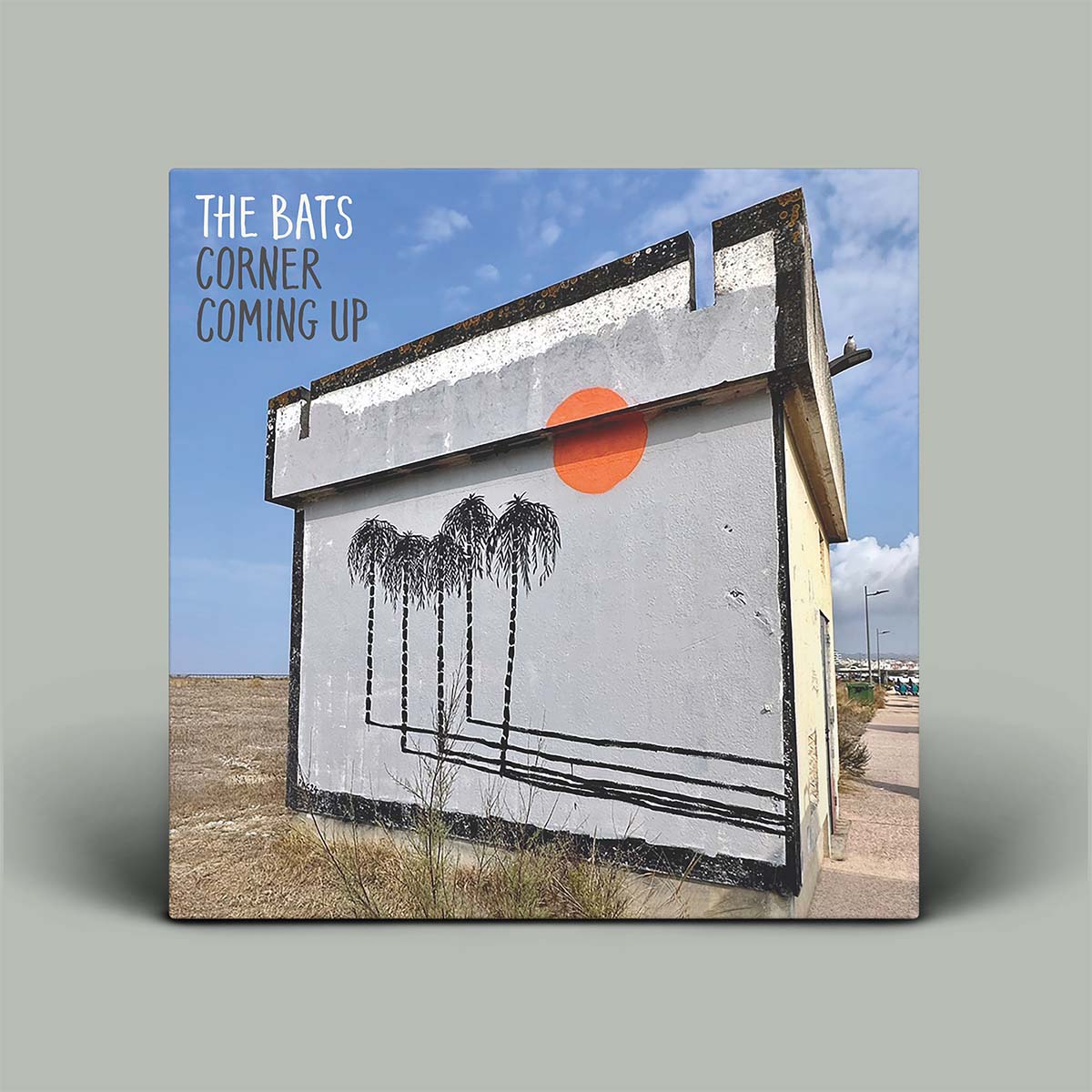 Album cover with a building, palm trees, and a red circle on a blue sky background.