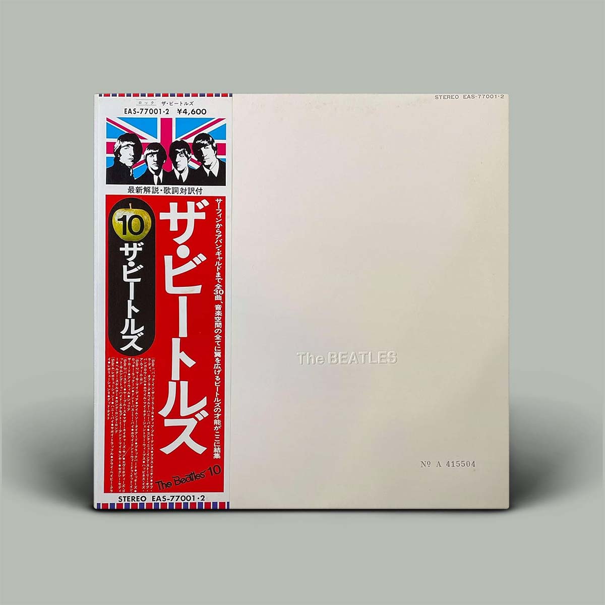 The Beatles 'White Album' Japanese vinyl record sleeve, featuring a beige cover with a prominent red and black vertical Japanese text panel on the left side, photographed on a neutral gray background.