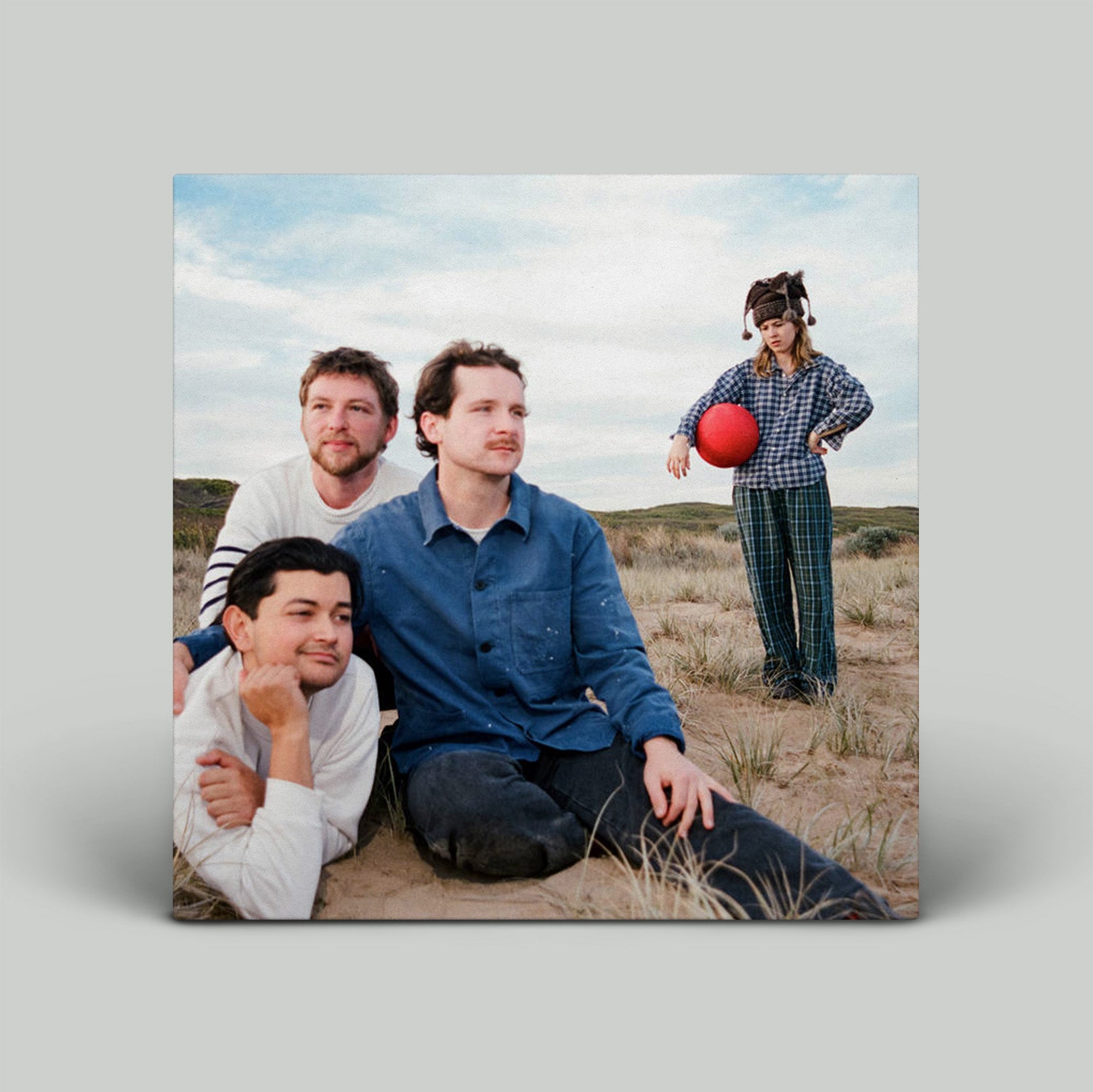 Four people in a desert setting with a child holding a red ball.