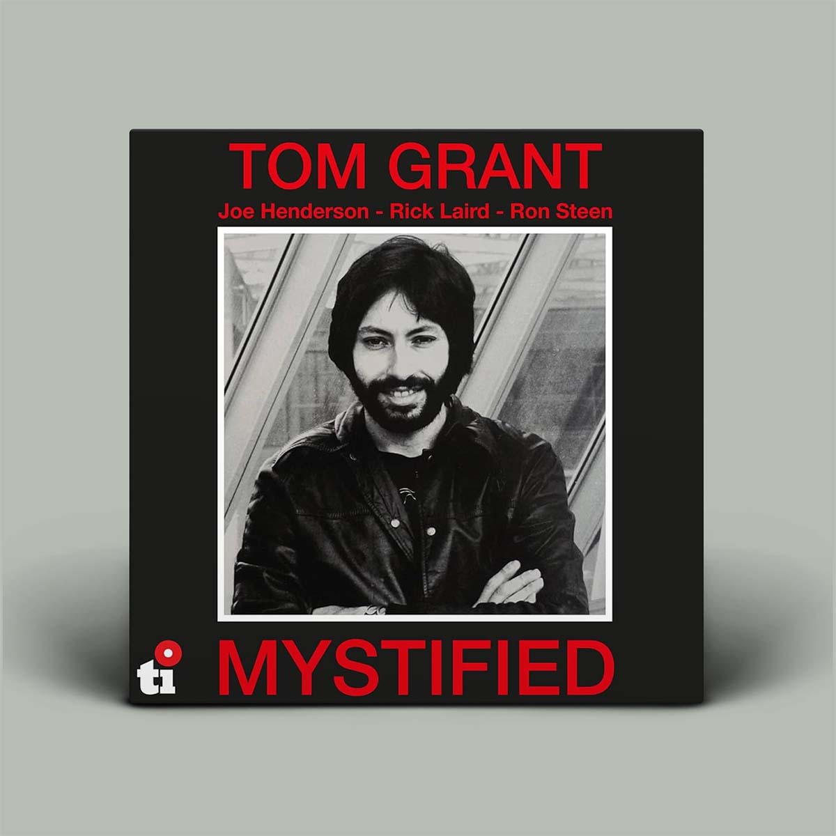 Album cover with a black and white photo of a person and text 'Tom Grant Mystified' on a gray background