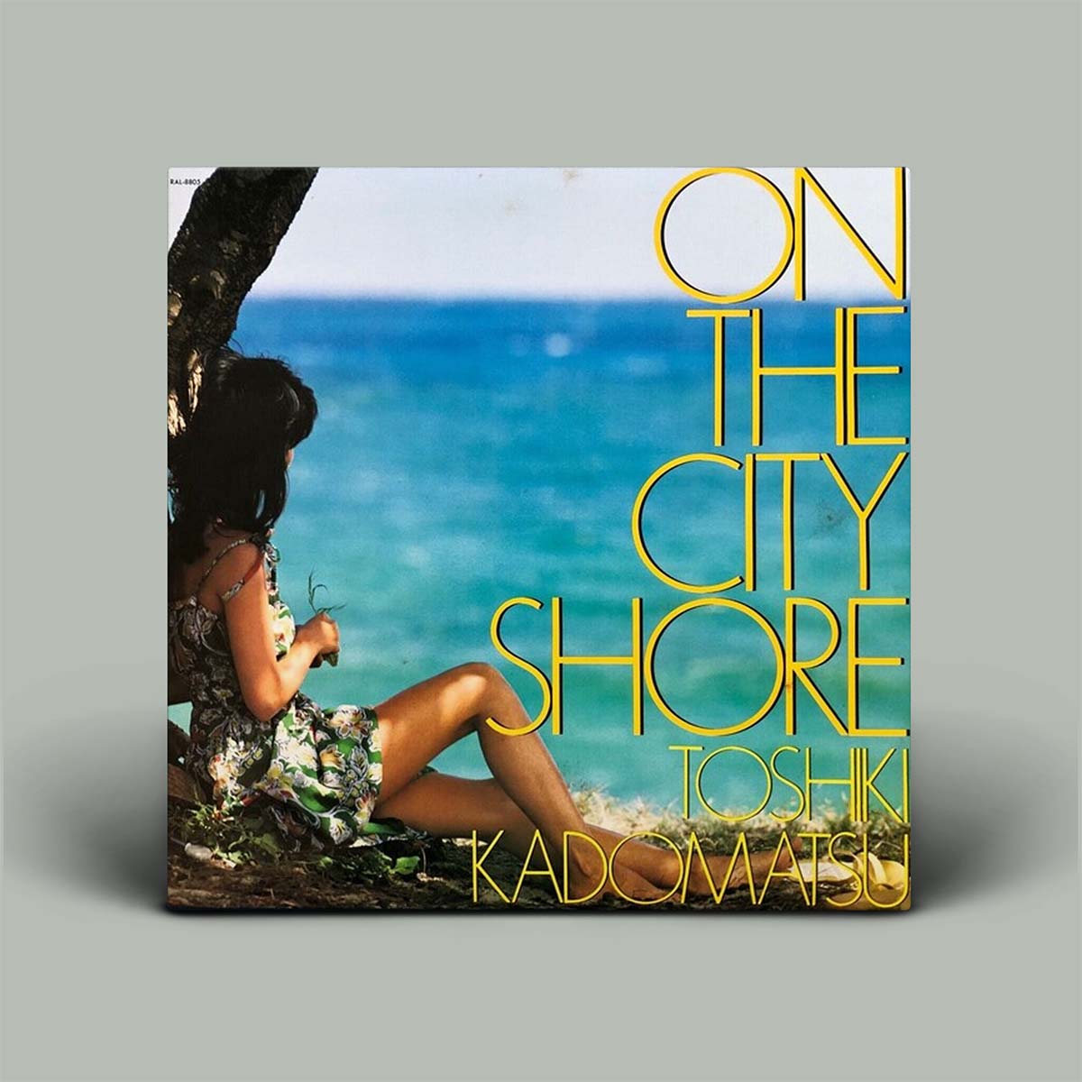 Album cover of 'On the City Shore' by Toshiki Kadoyama with a person sitting by the ocean.