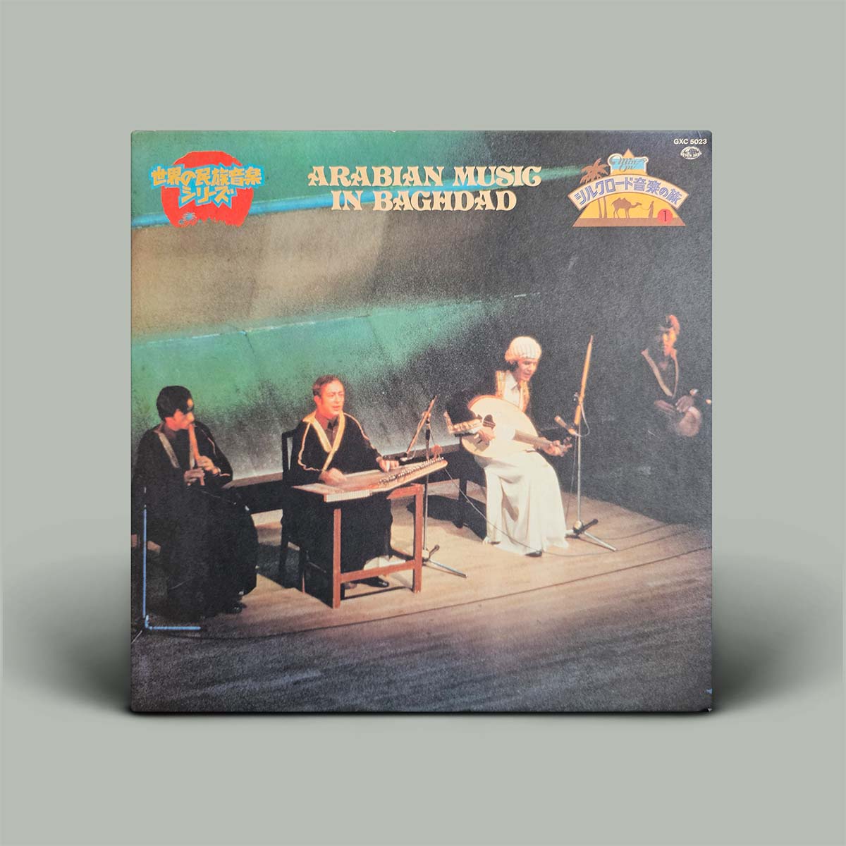 A vinyl record album titled 'Arabian Music in Baghdad' with a cover photograph of a live musical performance, photographed against a solid gray background.