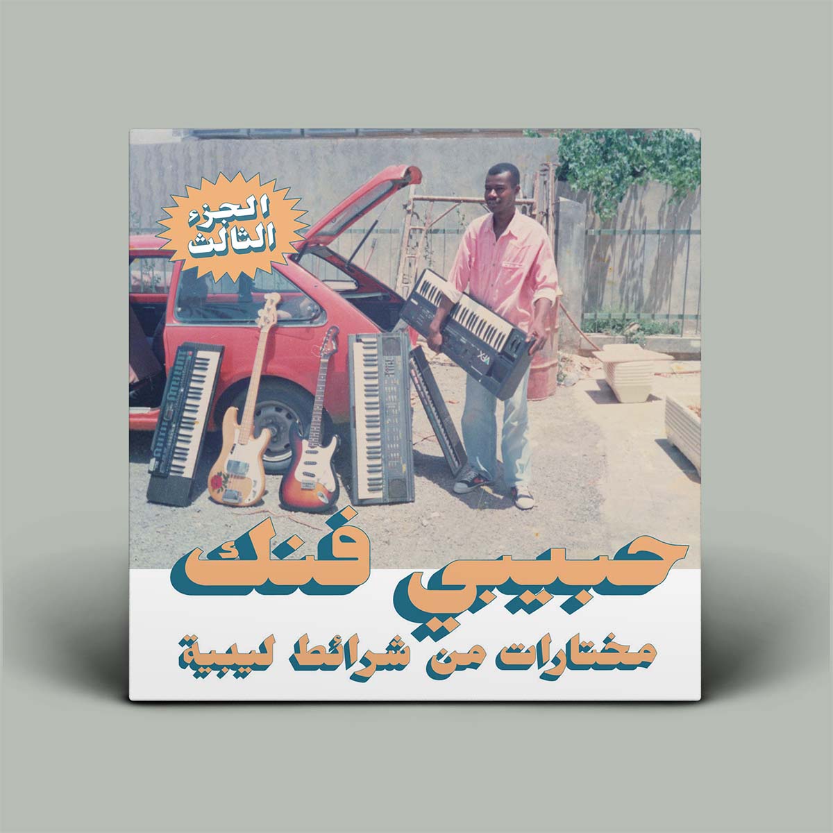 Album cover with a person holding a keyboard, guitars, and text in Arabic on a gray background