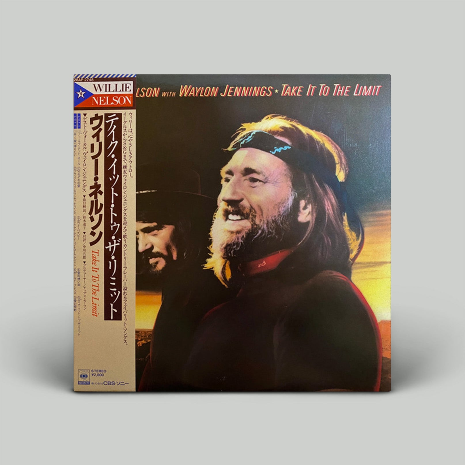 Vinyl record cover featuring a person with long hair and a bandana, with text and additional images on a gray background.