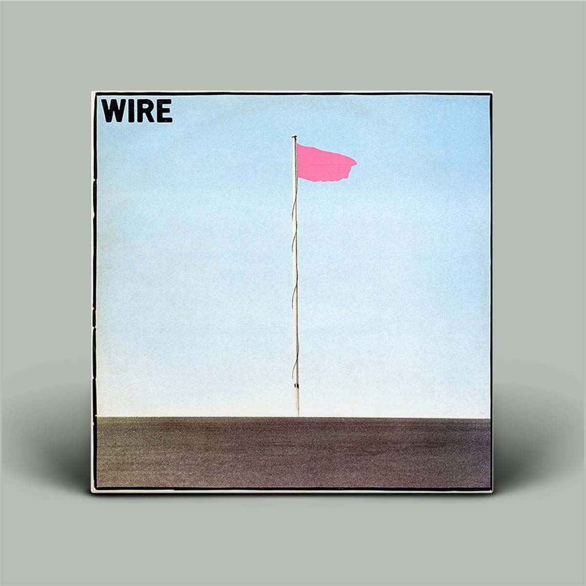Album cover with a pink flag on a pole against a blue sky and brown ground, featuring the word 'WIRE'.